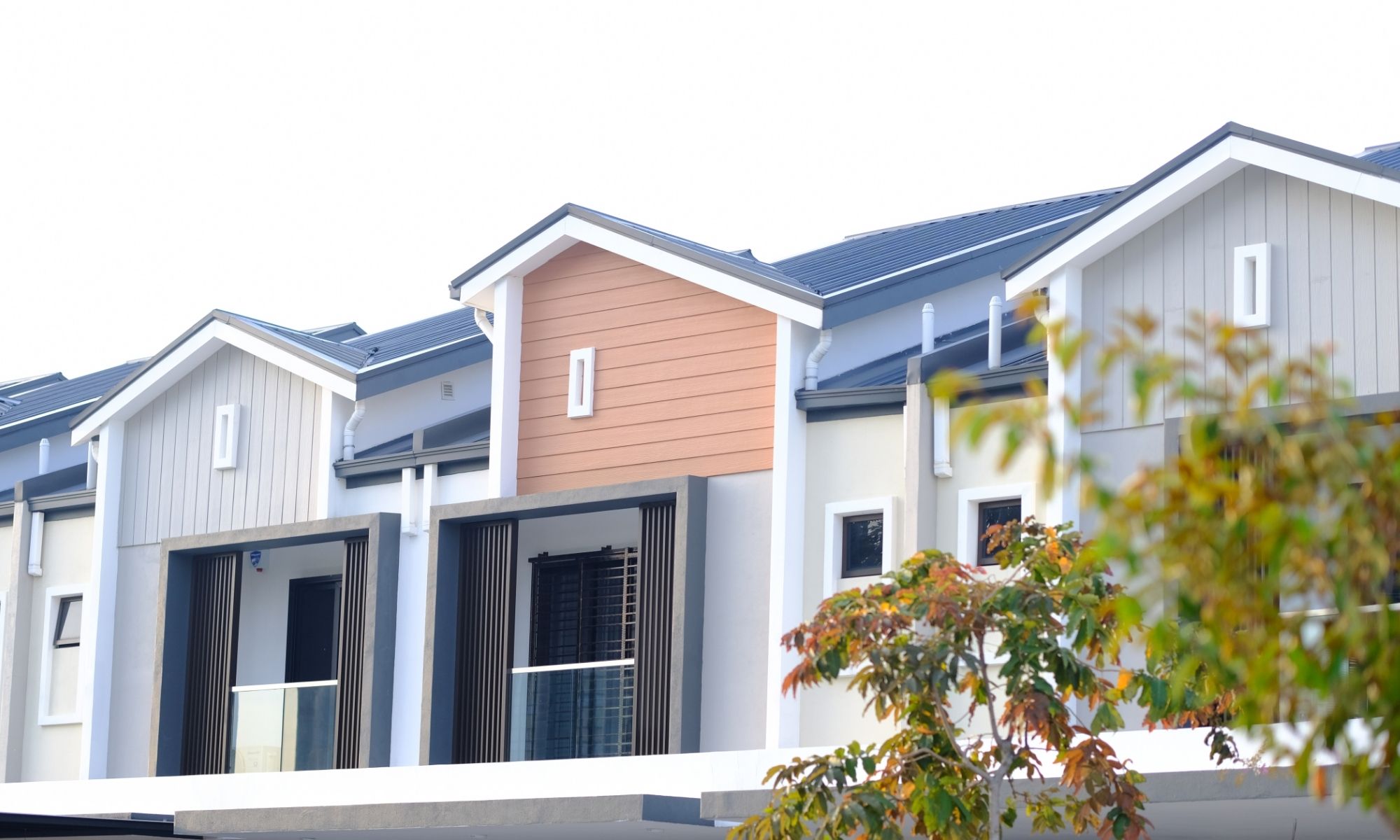 Modern two-story townhouses with large windows, neat exteriors, and a green tree—showing regular house washing.